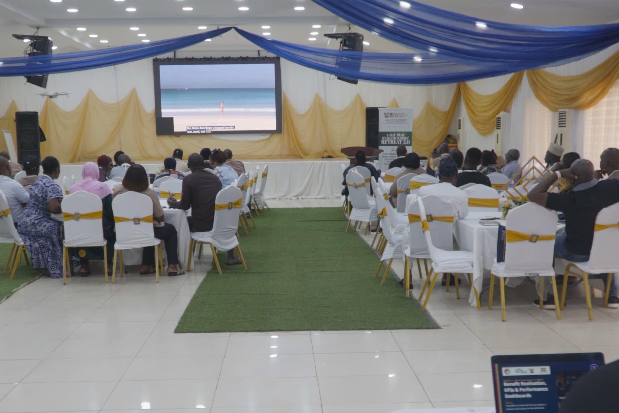 Participants seated at decorated tables facing a large screen