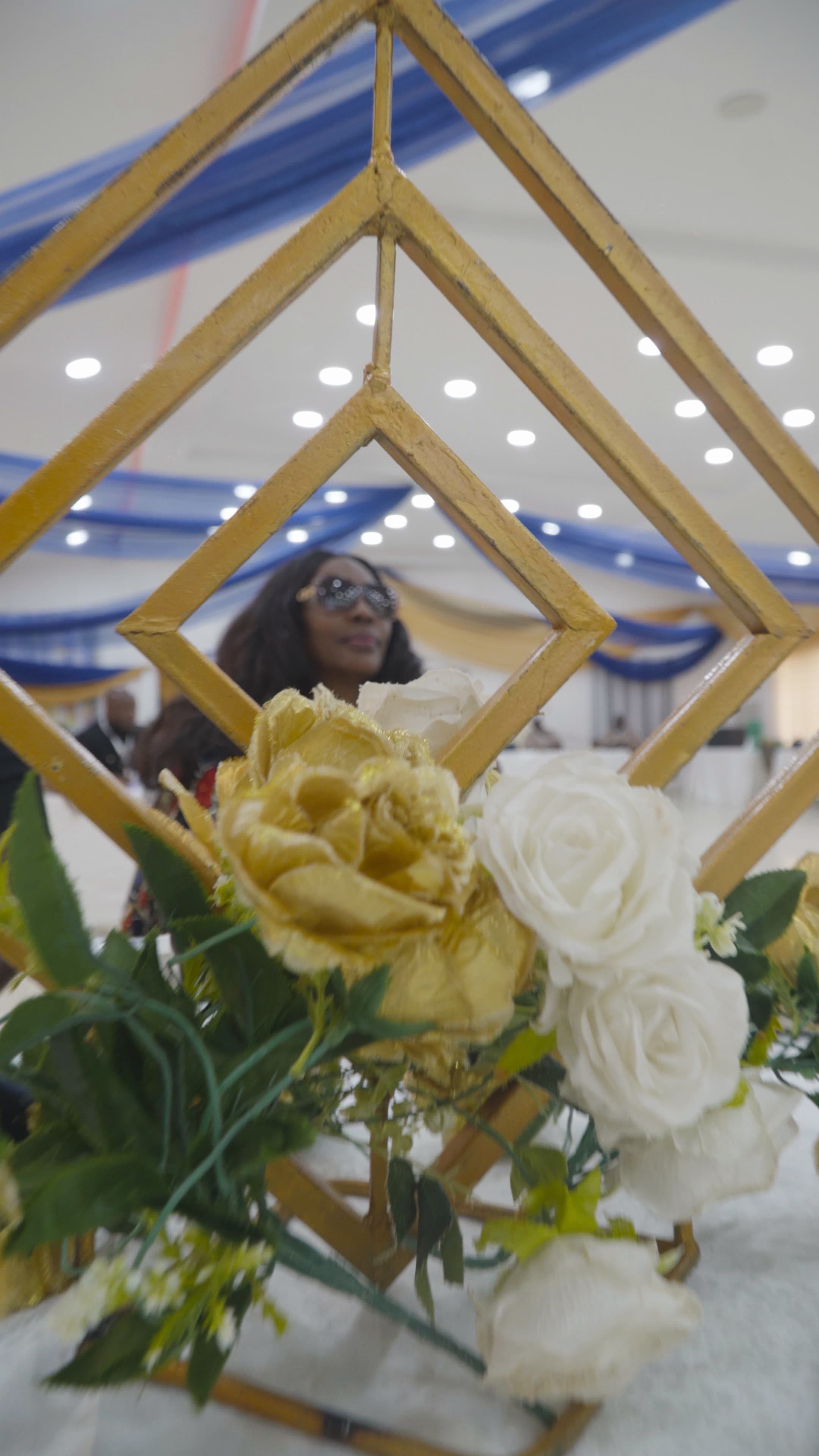 Gold floral table centrepiece with a person seen through its frame