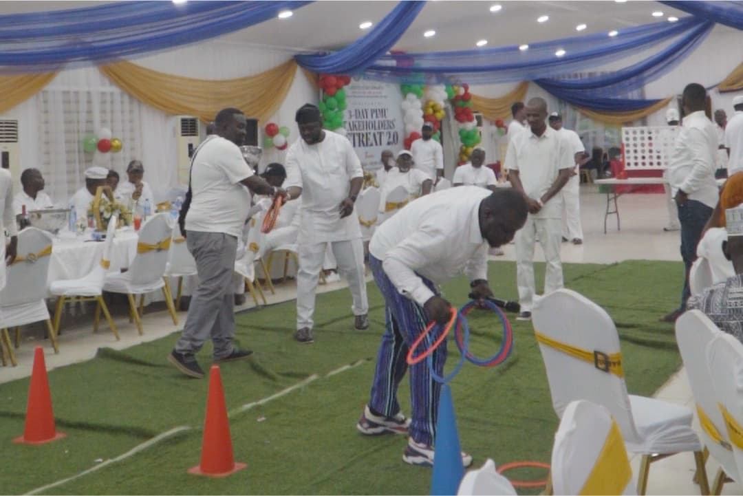Guests in white playing a game with cones and hoops on a green carpet